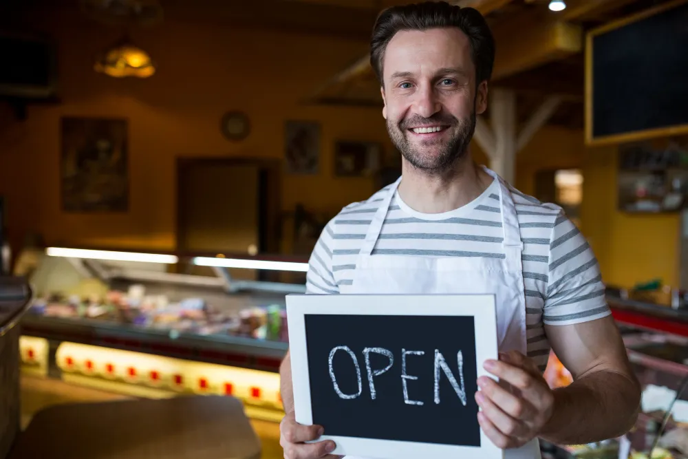 owner holding a open sign in the bakery shop