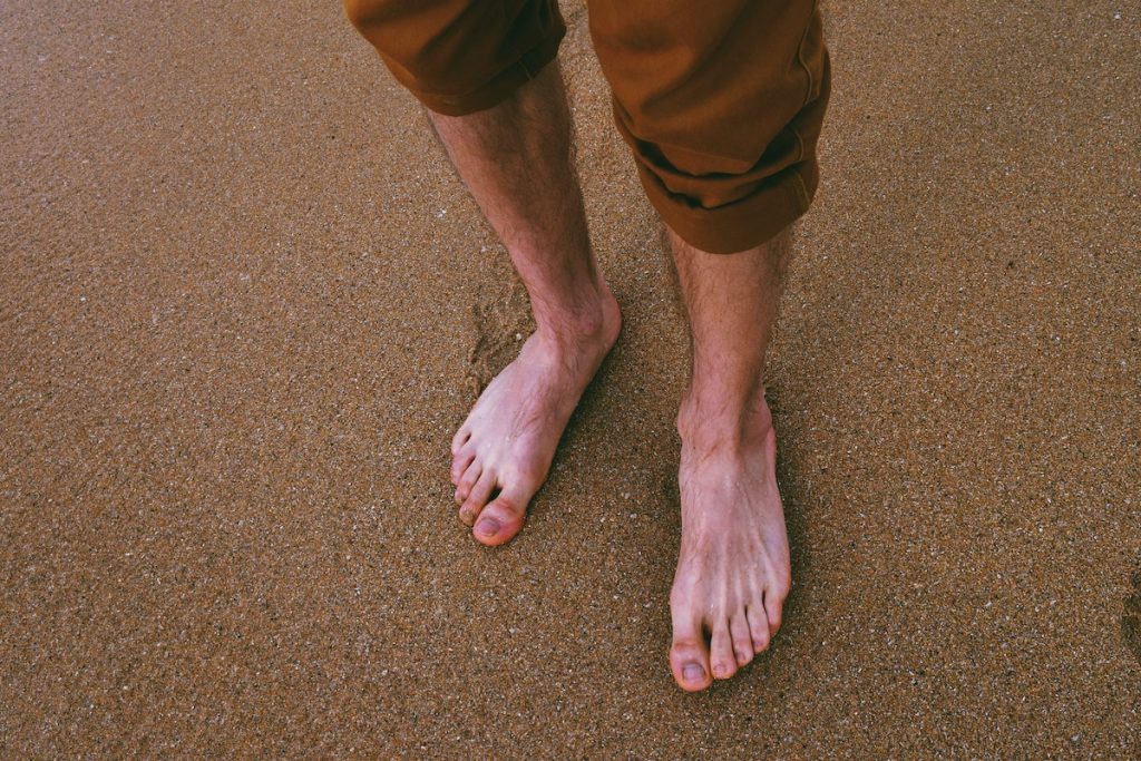 man's feet in the beach sand