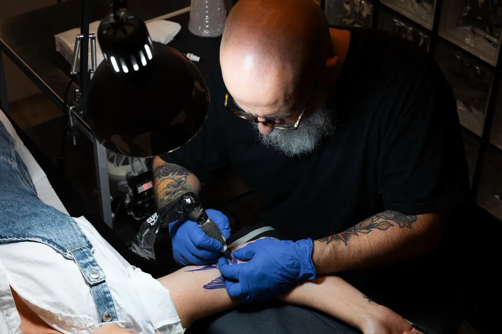 tattoo artist working on client tattoo