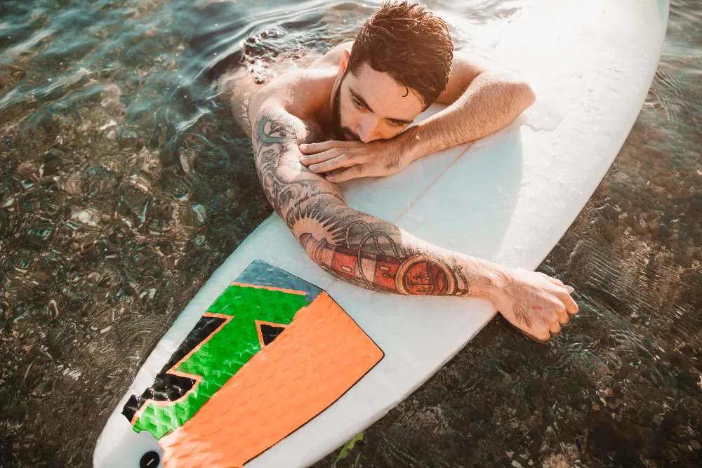 young man lying on surf board in water